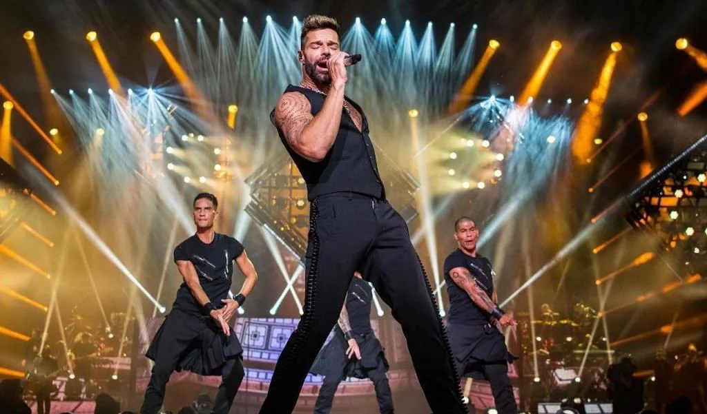 Artista en concierto con iluminación ámbar y bailarines